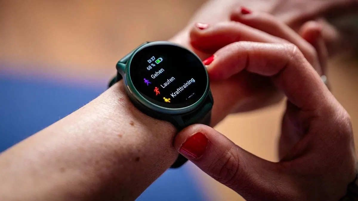 Eine Person tippt auf eine grüne Smartwatch, die am Handgelenk befestigt ist und die Optionen Gehen, Laufen und Krafttraining anzeigt.