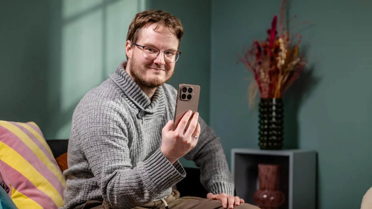 Michael sitzt mit dem Xiaomi 15T Pro in der Hand in einem Wohnzimmer und lächelt.