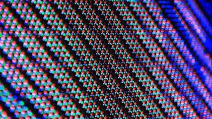 Detailaufnahme einer Bildschirmstruktur mit roten, grünen und blauen Pixeln auf schwarzem Grund, diagonal ausgerichtet.