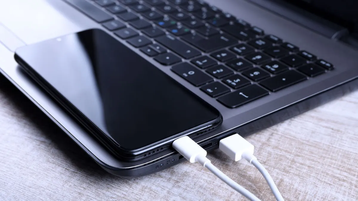 Ein Smartphone ist per USB-Kabel an einen Laptop angeschlossen.