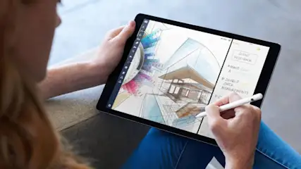 Eine Person hält ein Tablet mit einem Architekturentwurf und Notizen, wobei ein Stift auf dem Bildschirm verwendet wird.