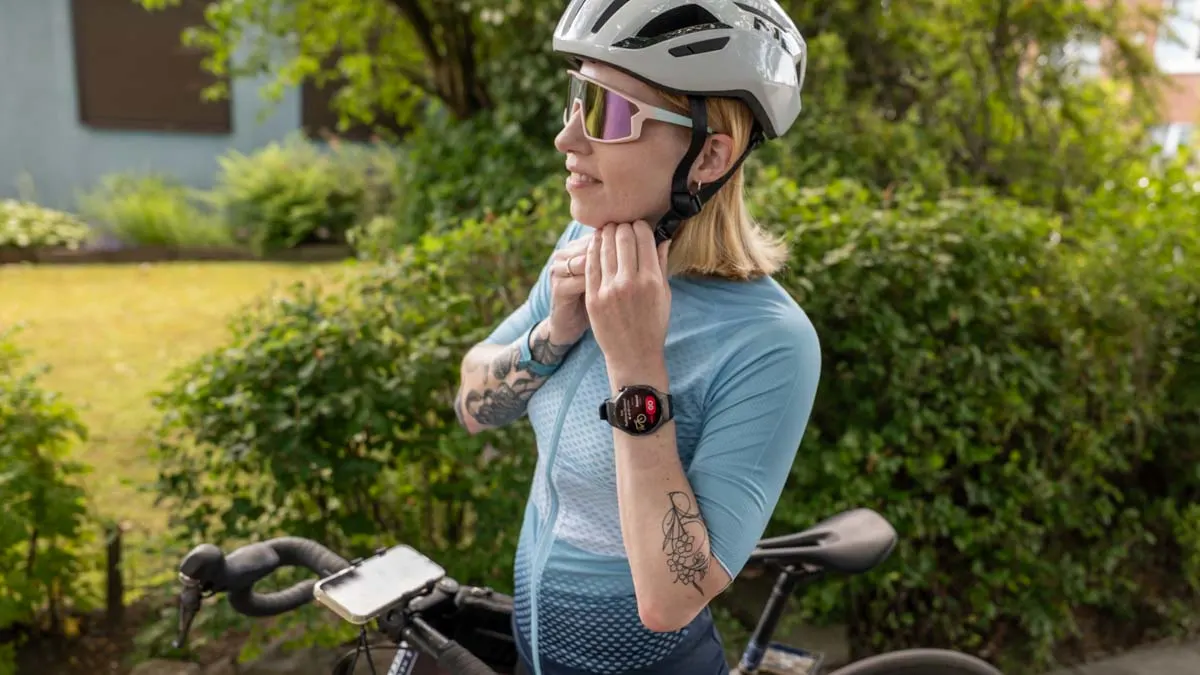Franzi steht vor ihrem Rennrad und schließt den Verschluss ihres Fahrradhelms.