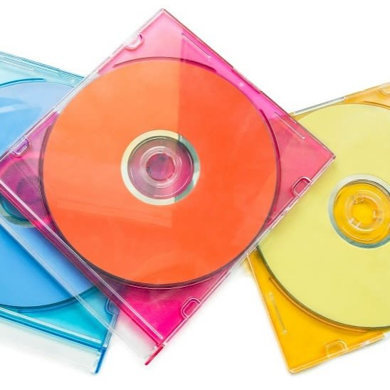 Drei CDs liegen in ihrer blauen, pinken und gelben Hülle aufeinander.