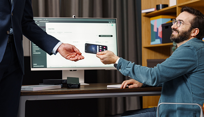 Ein Mann übergibt ein Smartphone an eine andere Person.