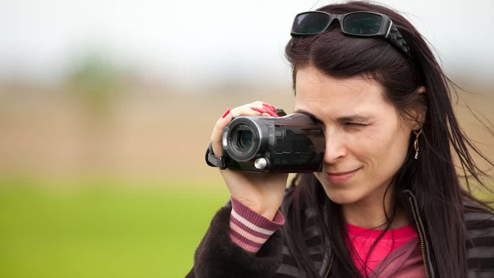 Eine Frau filmt mit einer Videokamera.
