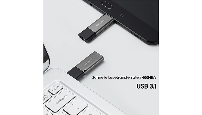Ein grauer USB-Stick ist mit einem schwarzen Smartphone verbunden, daneben ein Laptop mit weißer Tastatur. Text: "Schnelle Lesetransferraten 400MB/s USB 3.1".