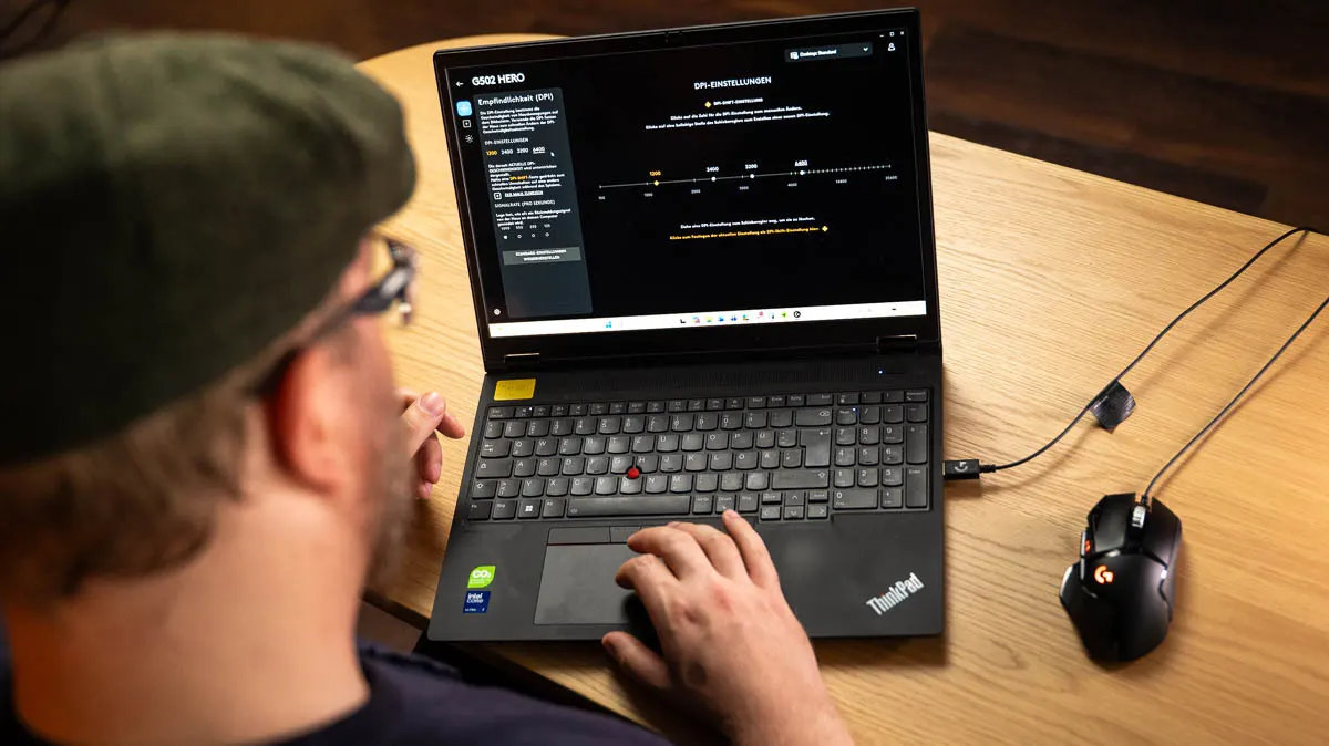 Andreas sitzt vor einem Laptop mit der Maus-Software zur Logitech G502 Hero, rechts neben dem Laptop liegt die Maus.