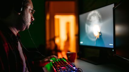 Spieler mit Gaming-Tastatur zockt an Gaming-Monitor