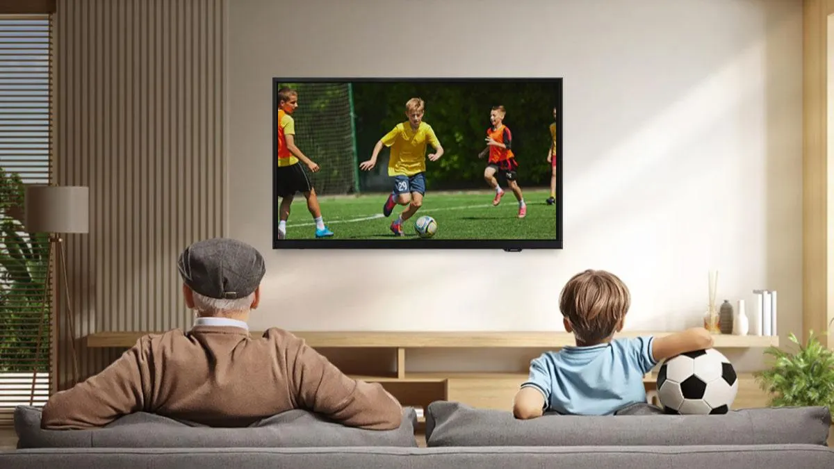 Ein älterer Mann und ein Junge sitzen auf einer Couch und gucken Fußball auf dem 32-Zoll-Fernseher Samsung GU32F6009F.