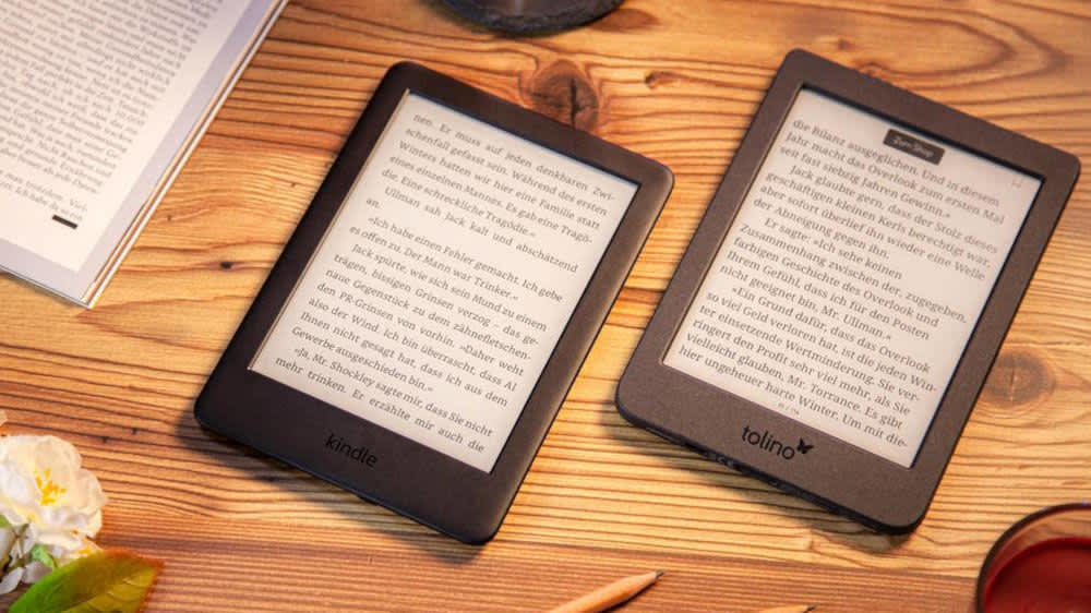 Ein Amazon-Kindle und ein Tolino-Page2 liegen auf einem Tisch nebeneinander.