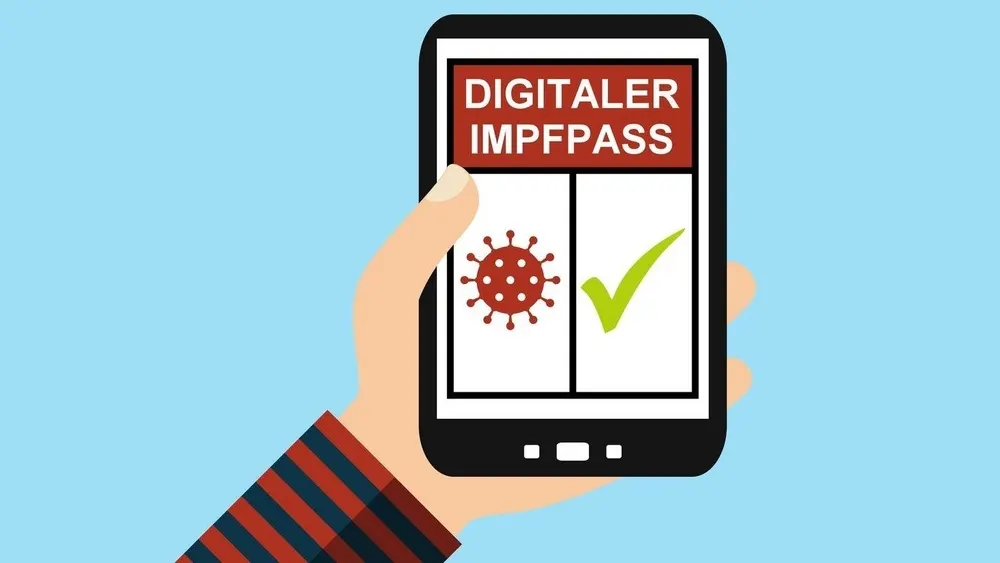 Hand hält Smartphone mit der Aufschrift "Digitaler Impfpass", Virus-Symbol und grünem Häkchen vor blauem Hintergrund.