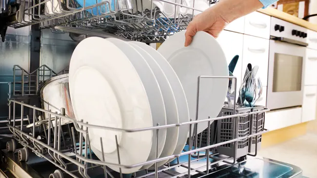 Eine Person holt sauberes Geschirr aus der Spülmaschine.
