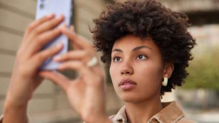 Eine Frau macht ein Selfie mit ihrem Smartphone.