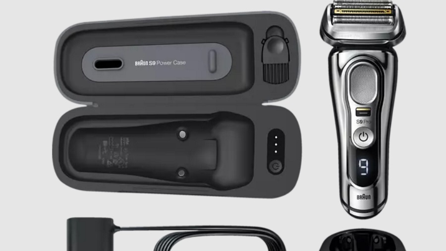 Ein grauer, offener Rasierer-Koffer und ein Rasierapparat mit Ladeständer und Kabel liegen auf einem hellen Hintergrund.