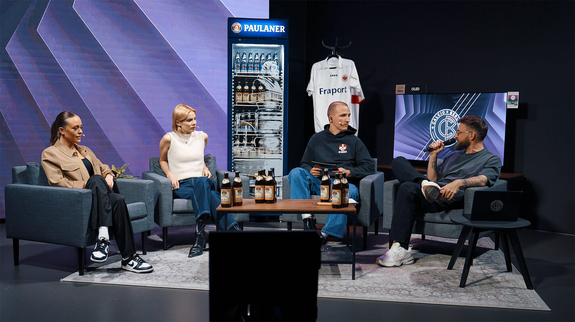 Diskussionsrunde: Vier Personen im TV-Studio: zwei Frauen mit heller Kleidung; zwei Männer in dunkler Kleidung. Stadtansicht im Hintergrund. 