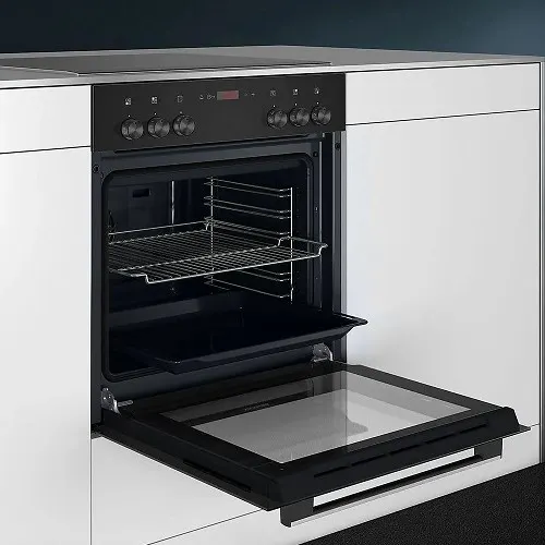 Ein schwarzer Ofen mit offener Glastür und einem Gitterrost im Inneren ist in eine weiße Küchenzeile eingebaut.