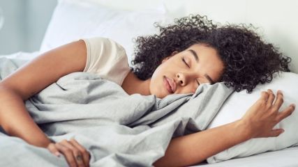 Eine junge Frau liegt im Bett und schläft friedlich.