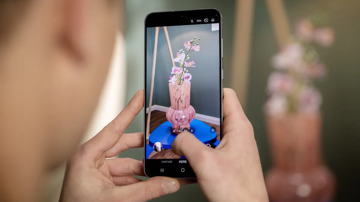 Alex fotografiert eine Blumenvase mit dem Smartphone Samsung Galaxy S25 FE.