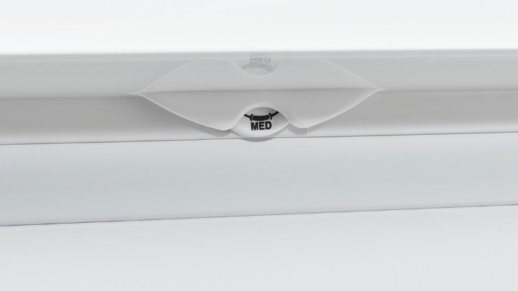 Ein weißes Gerät mit einer durchsichtigen Abdeckung. In der Mitte steht in schwarzer Schrift "MED".