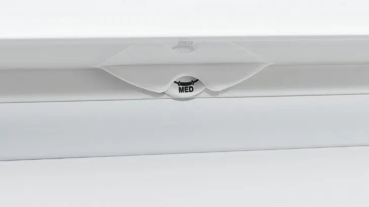 Ein weißes Gerät mit einer durchsichtigen Abdeckung. In der Mitte steht in schwarzer Schrift "MED".