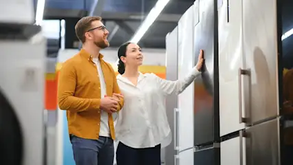 Ein Mann und eine Frau sehen sich Kühlschränke im Fachhandel an.