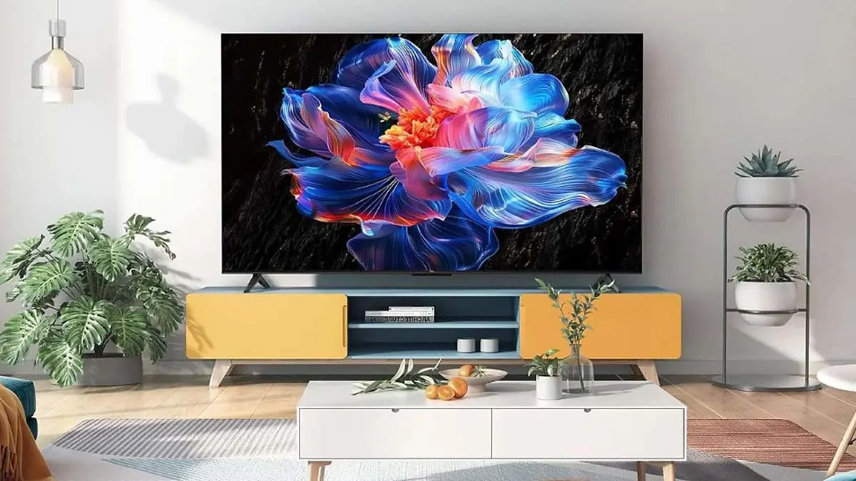 Der Fernseher TCL 65P6K steht auf einem gelben TV-Board. Auf dem Bildschirm ist eine bunte, abstrakte Blume zu sehen.