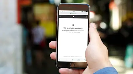 Ein Smartphone in der Hand zeigt eine Website mit der Nachricht "Wir sind bald wieder da." Der Hintergrund ist unscharf.