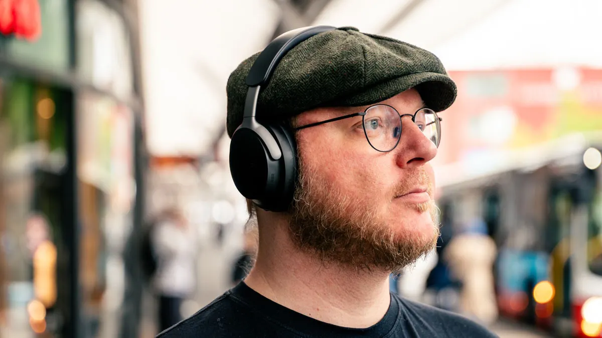 Andreas trägt den Bose QuietComfort Ultra an einer Bushaltestelle.