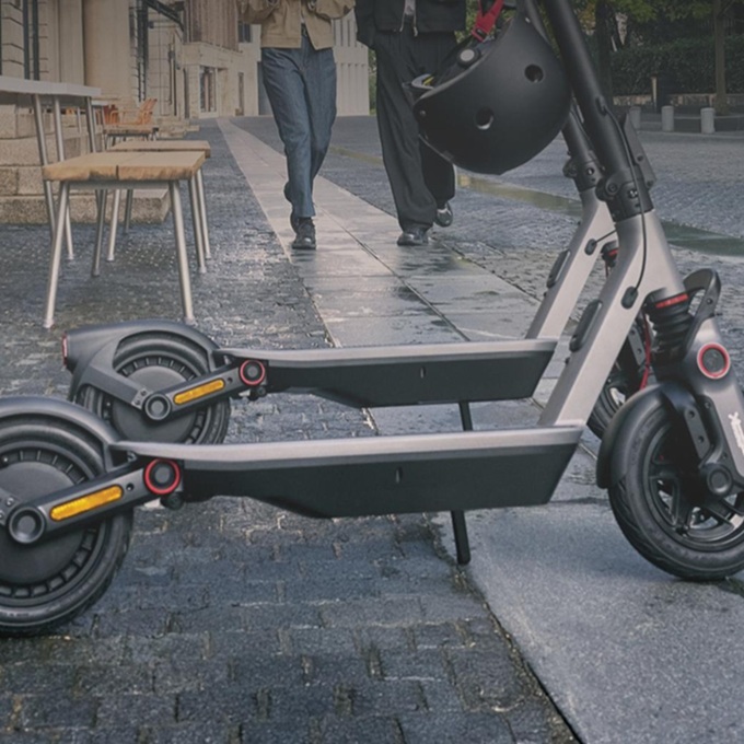 Person fährt einen SEGWAY Ninebot F3 Pro D E-Scooter über eine sonnige Stadtkreuzung