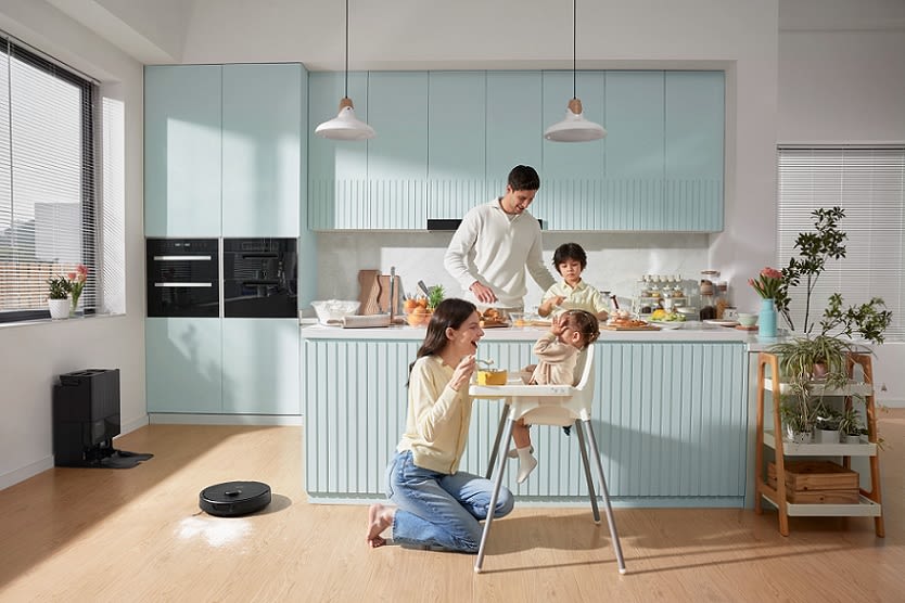 ROBOROCK Q Revo Saugroboter reinigt in Küche bei einer jungen Familie, die zeitgleich ihr Miteinander genießt