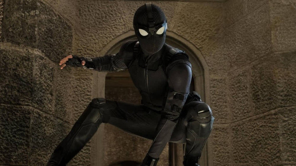 Spider-Man hockt mit einem schwarzen Kostüm vor einer Gebäudefassade.