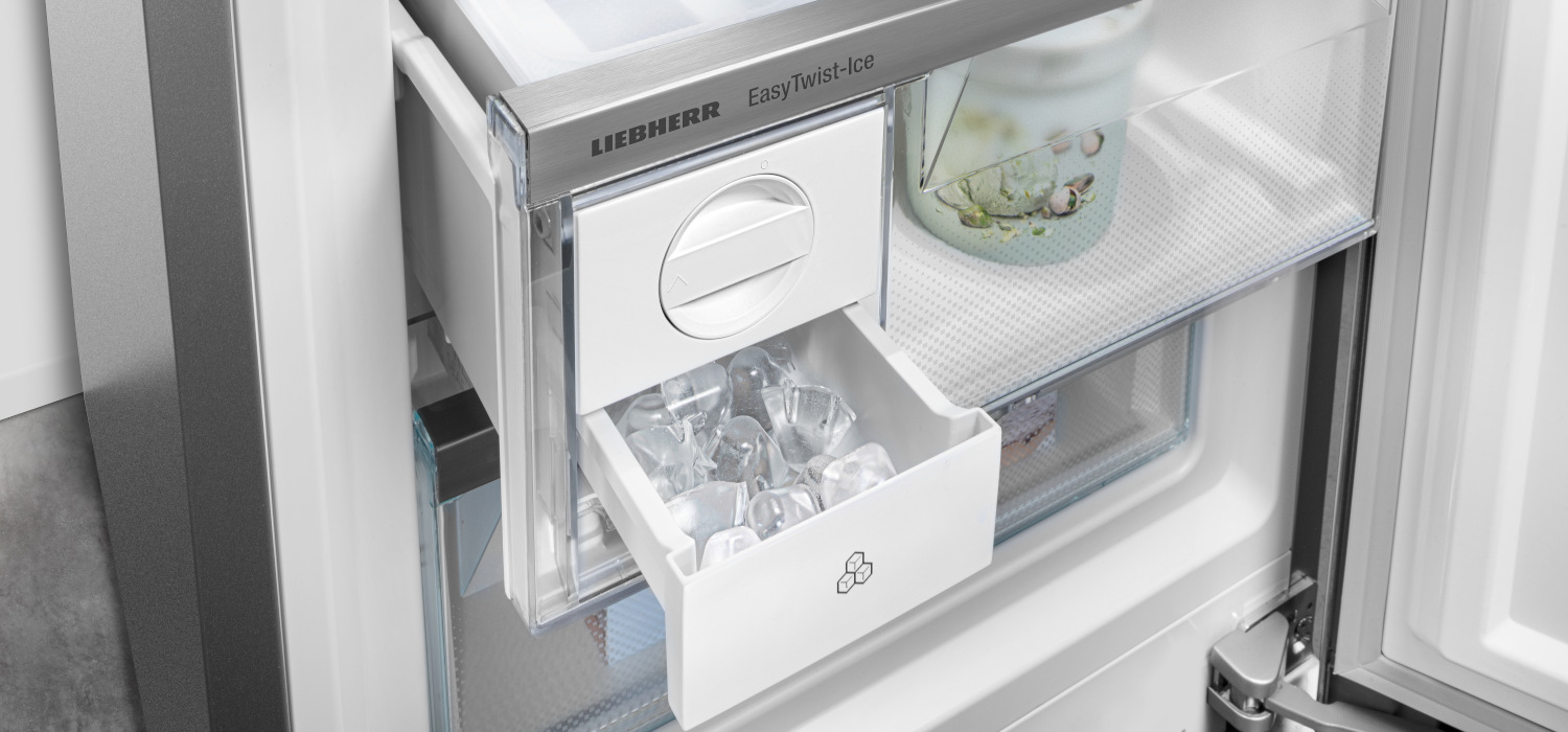 Ein Kühlschrank mit geöffneter Tür zeigt einen Eiswürfelbehälter, der mit Eis gefüllt ist, und Regale.