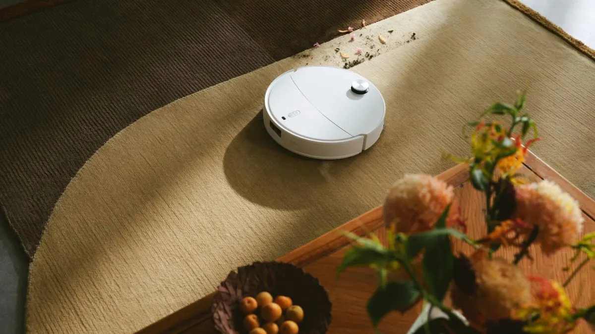 Der Saugroboter Roborock Qrevo Curv 2 ProX saugt Blumenerde von einem Teppich.