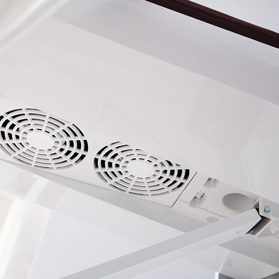 Zwei runde, weiße Lüftungsgitter mit schwarzen Akzenten sind in einer weißen Oberfläche eingelassen. Eine braune Leiste ist sichtbar.