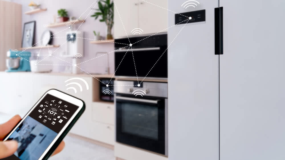 Ein Smartphone wird zur Steuerung vernetzter smarter Küchengeräte genutzt.