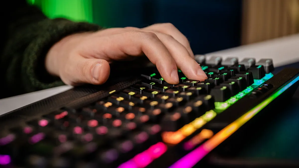 Eine Hand tippt auf der mechanischen Tastatur Corsair Gaming K95 RGB Platinum, die bunt leuchtet.