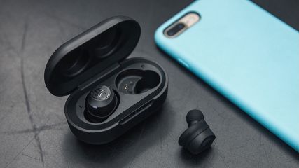 Schwarze Bluetooth Kopfhörer liegen neben einem Smartphone
