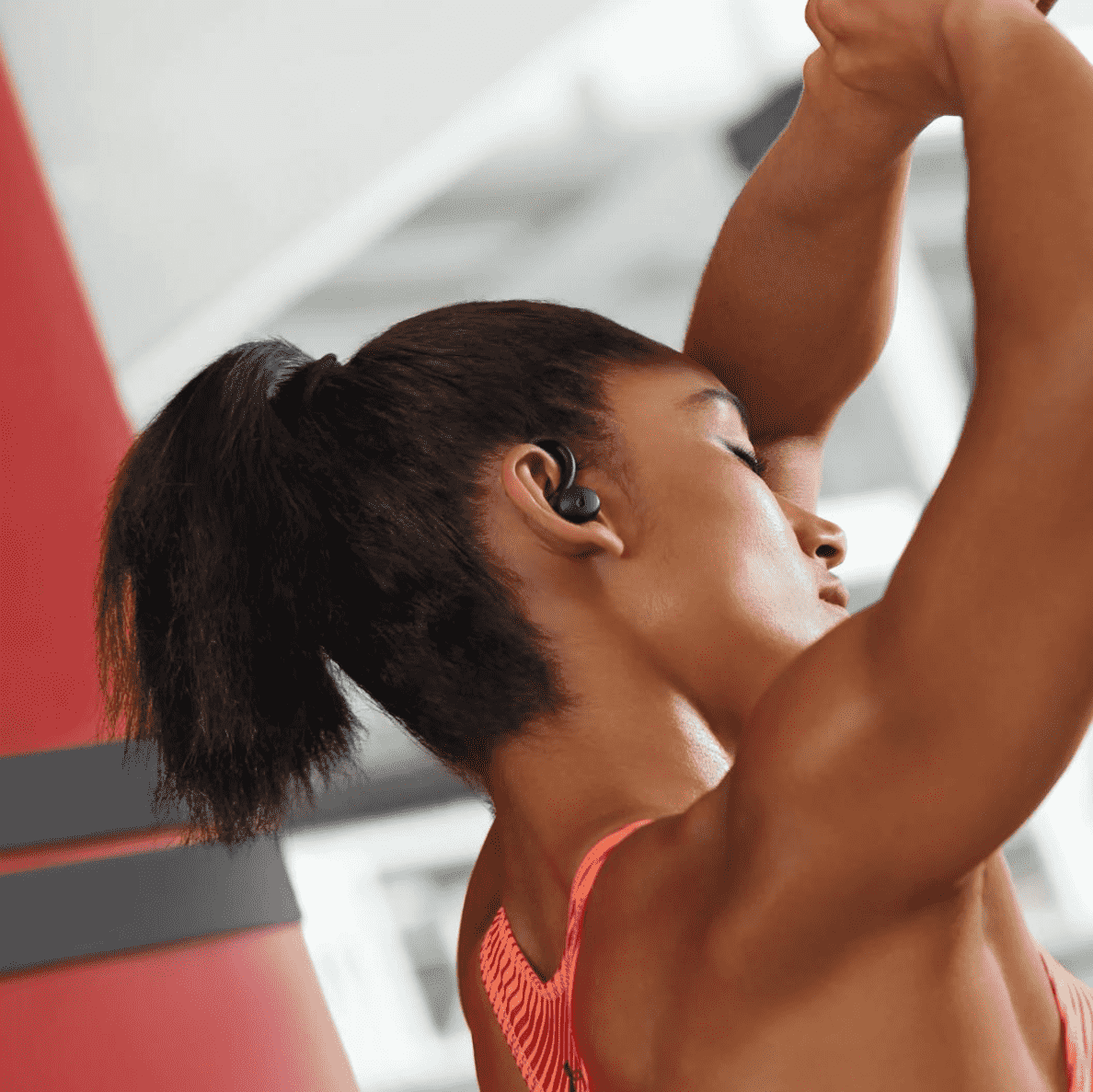 Junge Frau mit Pferdeschwanz ist im Fitnessstudio und trägt die ANKER Soundcore Sport X10 In-ear Kopfhörer