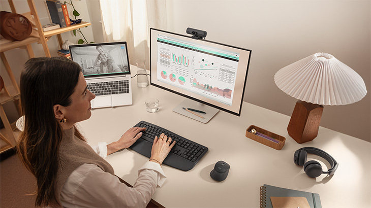 Moderner Arbeitsplatz mit ergonomischen Eingabegeräten, großem Monitor und Videokonferenz-Setup. Die Kombination aus Maus, Tastatur, Webcam und Headset unterstützt komfortables und produktives Arbeiten im Büro oder Homeoffice.