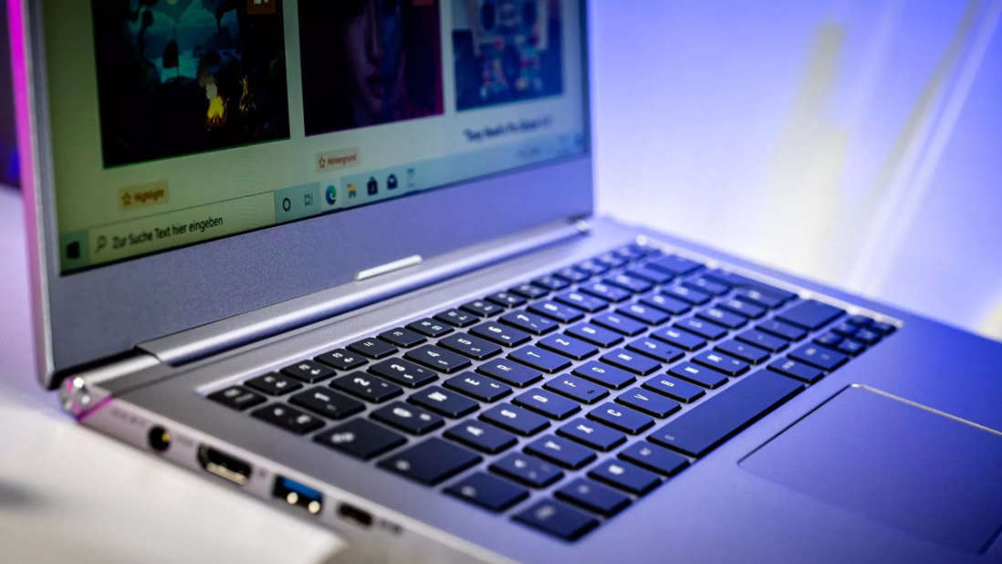 Ein Laptop mit beleuchteter Tastatur steht auf einem Schreibtisch.