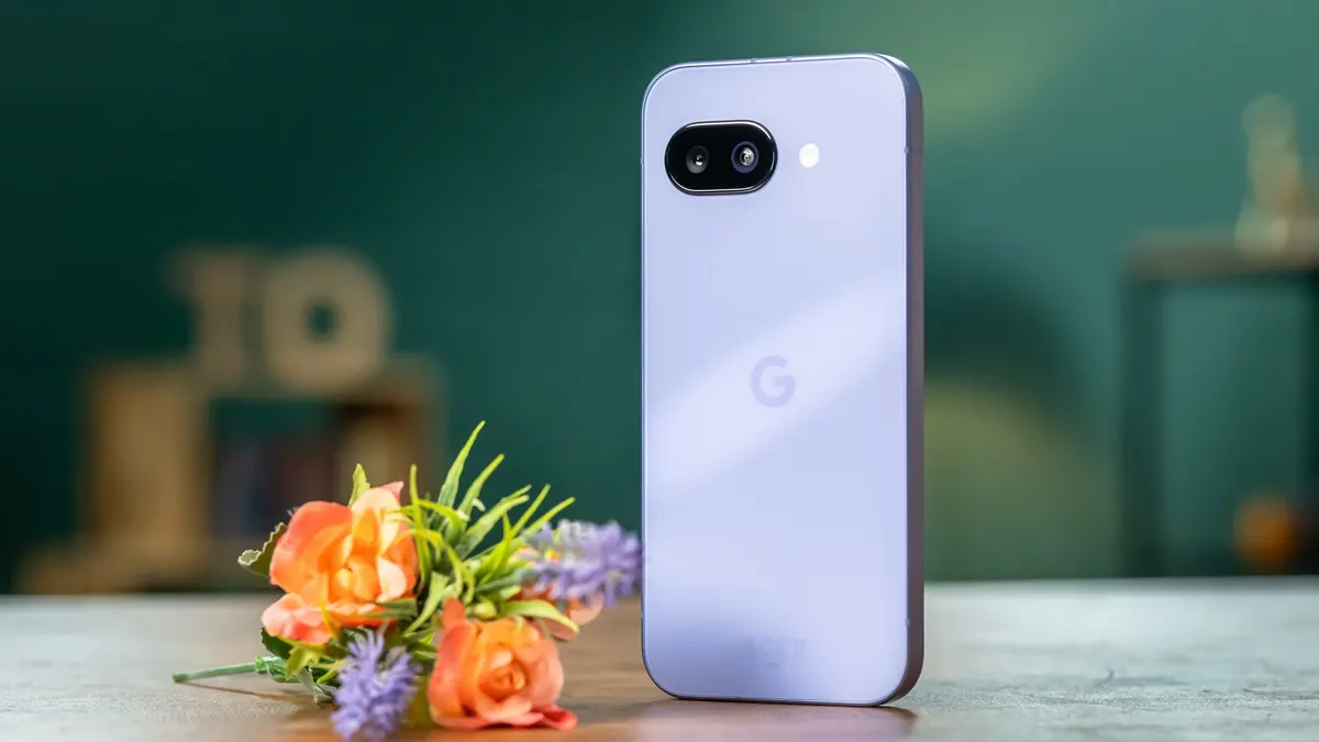 Ein lila Handy mit zwei Kameras liegt neben einem Blumenstrauß mit orangefarbenen Rosen und lila Lavendel auf einem Tisch.