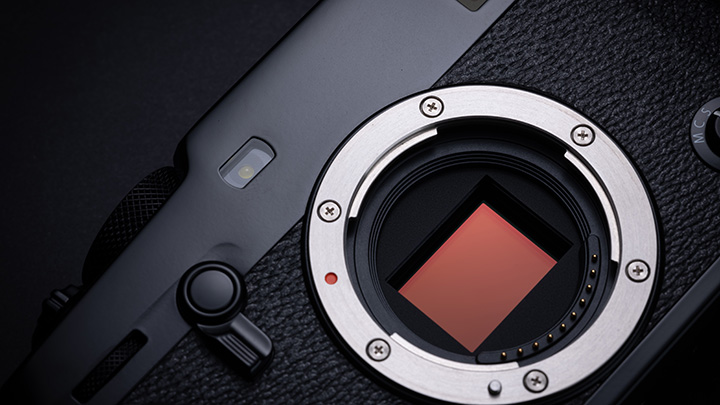 Nahaufnahme einer schwarzen Kamera mit silbernem Objektivanschluss und rotem Sensor.