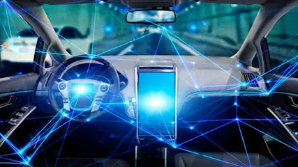 Innenraum eines Autos mit Lenkrad, Armaturenbrett und großem Bildschirm, verbunden durch blaue Linien. Straße im Hintergrund.