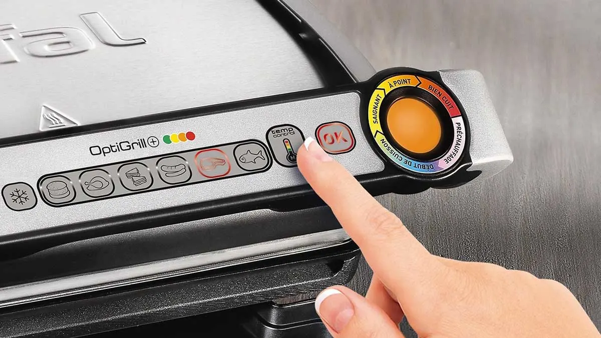 Eine Person drückt eine Taste auf dem Bedienfeld des Tefal OptiGrill+ GC712D.