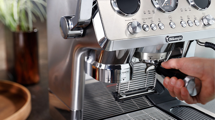 Moderne Siebträgermaschine auf einer Kücheninsel, umgeben von frisch zubereiteten Kaffees in einem hellen, stilvollen Wohnraum.