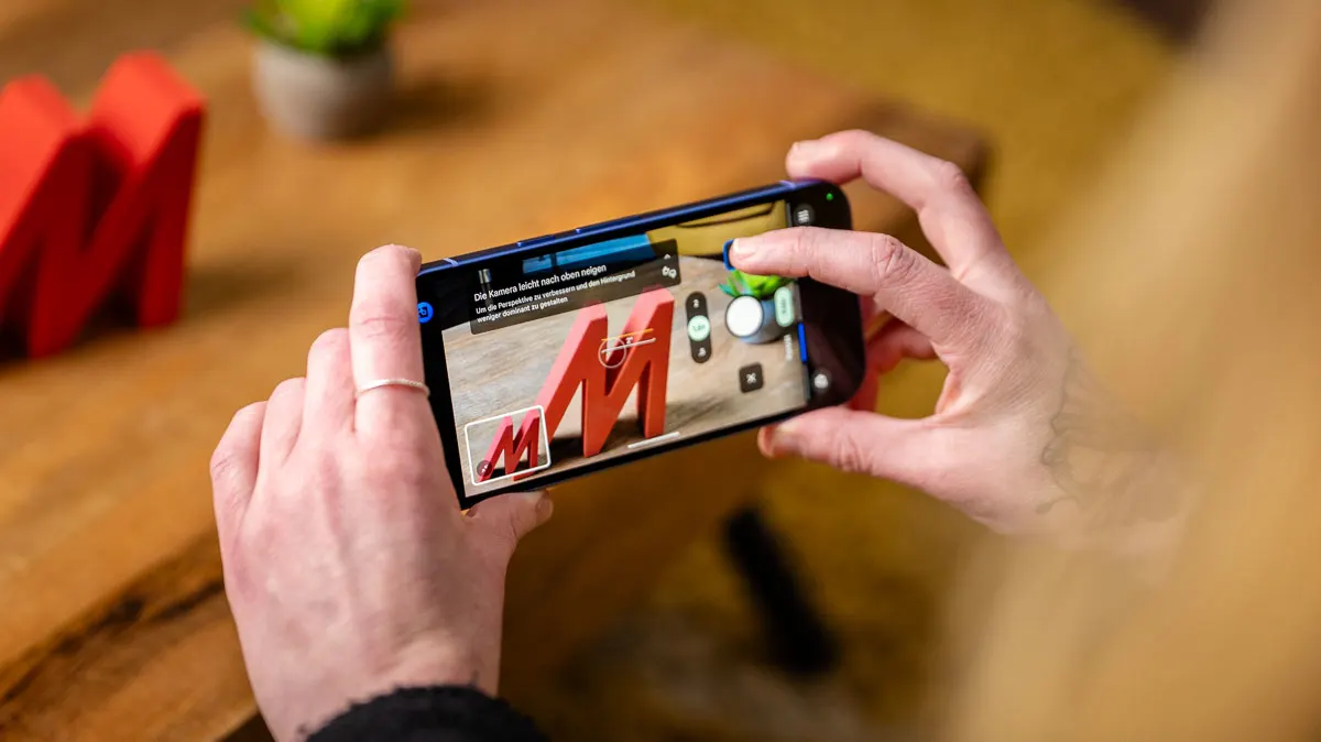 Der Kamera-Coach des Pixel 10a gibt Franzi Tipps zum Fotografieren eines roten „M“-Deko-Buchstabens.