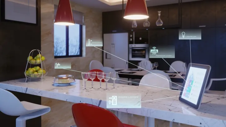 Moderne Küche mit Tisch, Stühlen, Tablet, Obstschale, Gläsern und roten Hängelampen unter Deckenbeleuchtung. Fenster im Hintergrund.