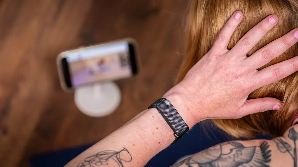 Franzi trägt das Fitbit Air am linken Handgelenk und macht eine Mobilitätsübung aus der Google-Health-App.