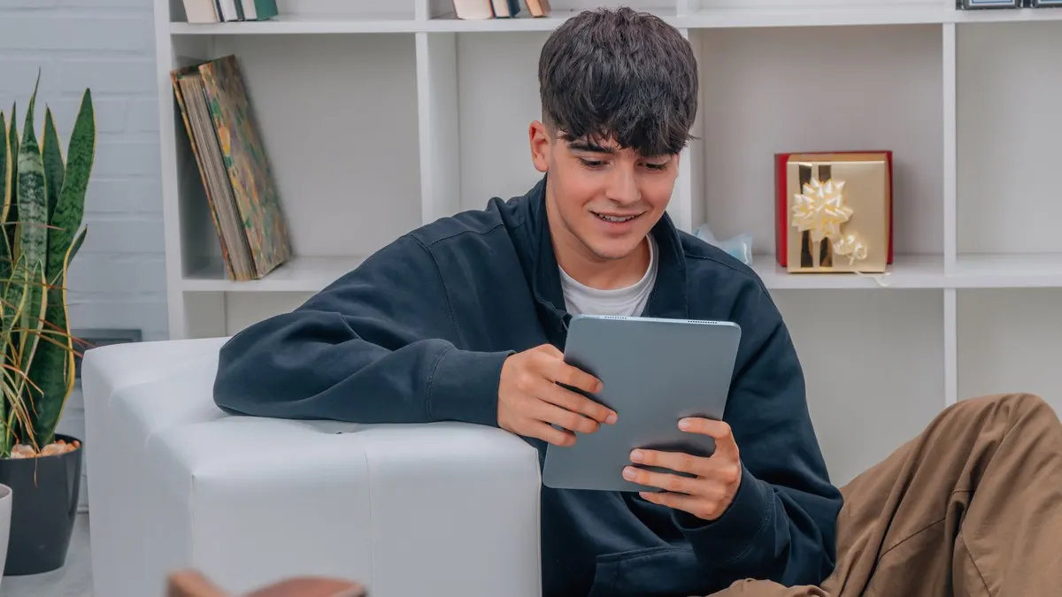 Ein Schüler blickt lächelnd auf ein Tablet.