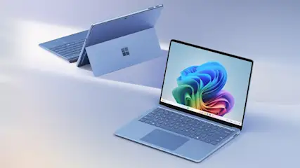Zwei hellblaue Microsoft Surface Laptops, einer mit geöffnetem Bildschirm, der andere im Hintergrund mit sichtbarer Tastatur.